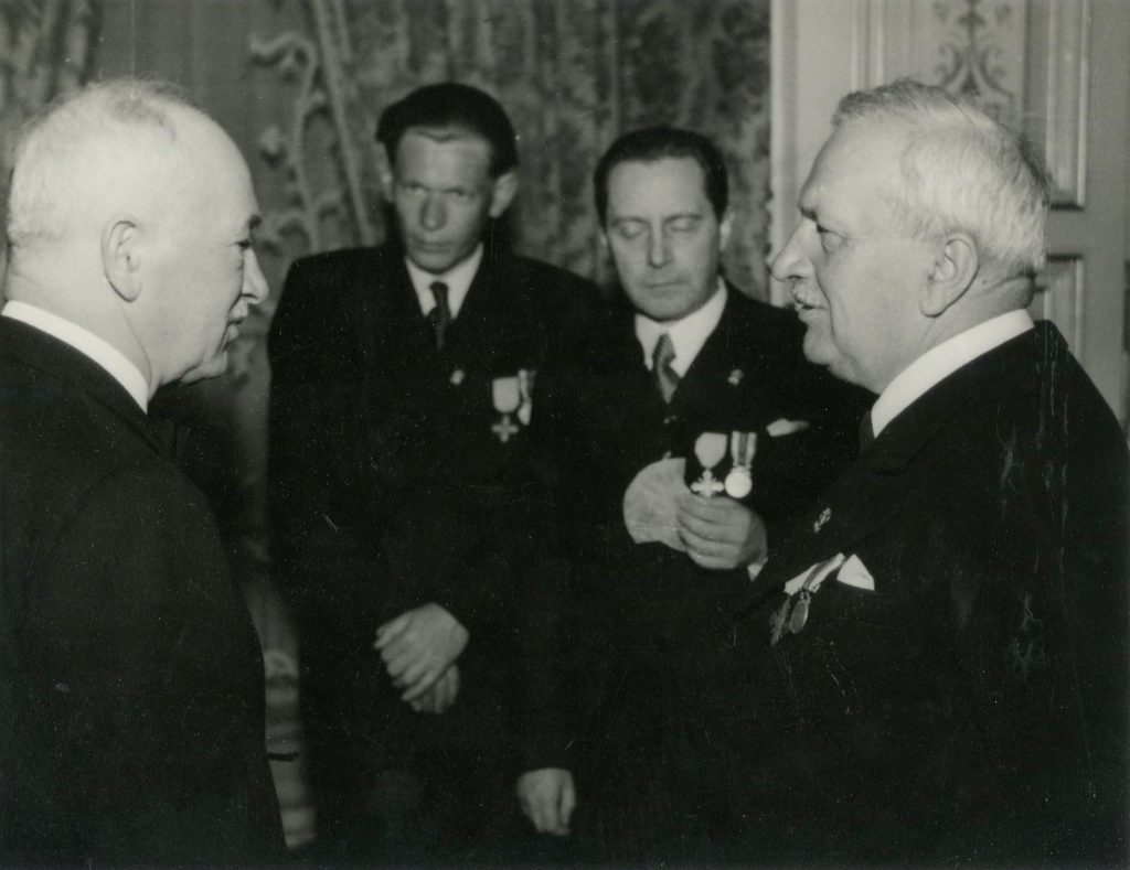 Prezident E. Beneš hovoří na slavnostním setkání k výročí Pražského povstání s bývalým předsedou ČNR A. Pražákem. V pozadí stojí J. Smrkovský.