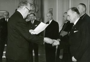 Ministr vnitra V. Nosek předává v Trůnním sále Pražského hradu primátorovi Prahy P. Zenklovi klíč od korunovačních klenotů uložených v chrámu sv. Víta.