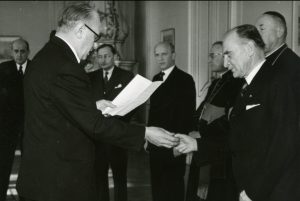 Ministr vnitra V. Nosek předává v Trůnním sále Pražského hradu primátorovi Prahy P. Zenklovi (vpravo) klíč od korunovačních klenotů uložených v chrámu sv. Víta.